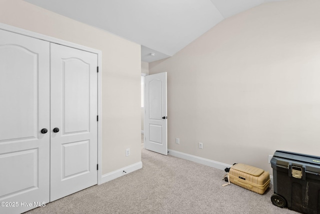 interior space featuring light colored carpet, vaulted ceiling, and a closet