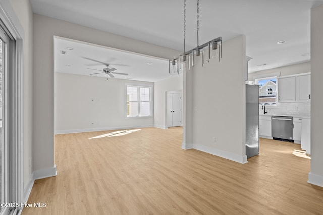 unfurnished living room with ceiling fan, sink, and light wood-type flooring