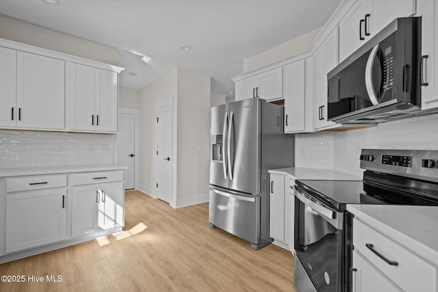 kitchen with white cabinetry, appliances with stainless steel finishes, light hardwood / wood-style floors, and backsplash