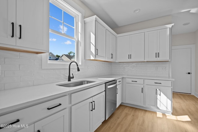 kitchen featuring dishwasher, sink, white cabinets, and light hardwood / wood-style floors