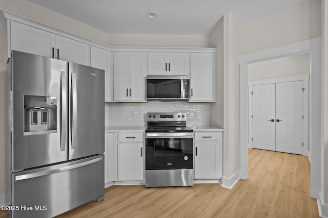 kitchen with stainless steel appliances, white cabinetry, tasteful backsplash, and light hardwood / wood-style flooring