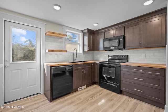 kitchen with sink, light hardwood / wood-style floors, butcher block countertops, and black appliances