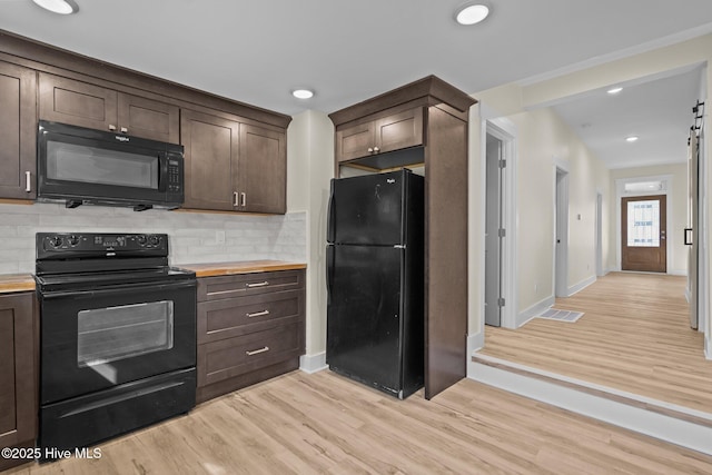 kitchen featuring backsplash, dark brown cabinetry, light wood-type flooring, and black appliances