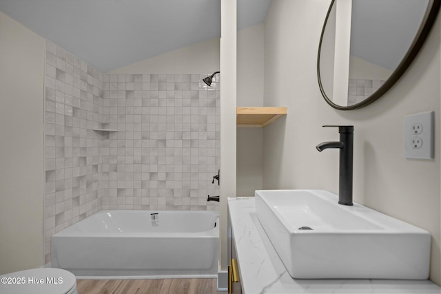 full bathroom featuring lofted ceiling, toilet, sink, tiled shower / bath combo, and hardwood / wood-style flooring