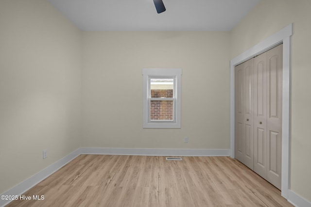 unfurnished bedroom with ceiling fan, light wood-type flooring, and a closet