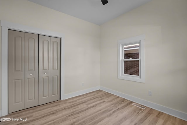 unfurnished bedroom with vaulted ceiling, light hardwood / wood-style floors, a closet, and ceiling fan