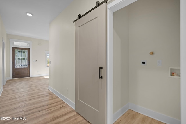 hallway with a barn door and light hardwood / wood-style flooring