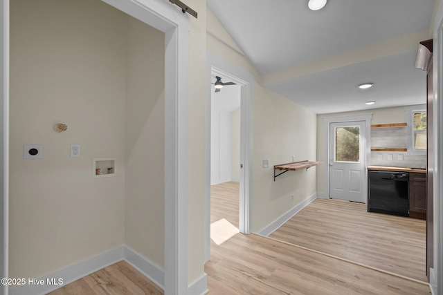 corridor featuring lofted ceiling, a barn door, and light hardwood / wood-style flooring