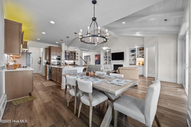 dining space with vaulted ceiling with beams, dark wood-type flooring, built in features, and an inviting chandelier