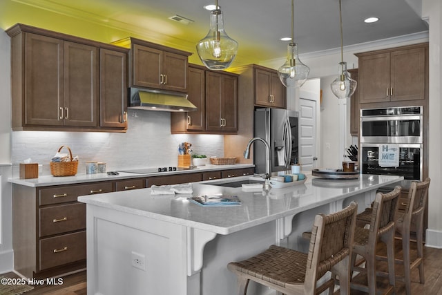 kitchen with sink, hanging light fixtures, a center island with sink, a kitchen breakfast bar, and stainless steel appliances