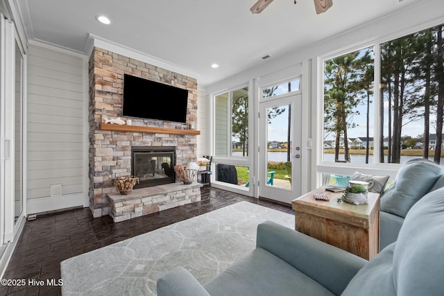 living room with ornamental molding, a stone fireplace, ceiling fan, and wood walls