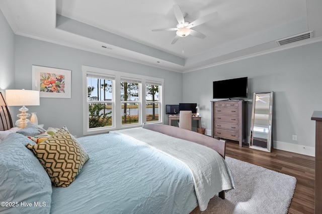 bedroom featuring a raised ceiling, dark wood-type flooring, and ceiling fan