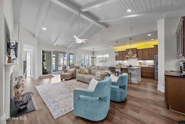 living room with high vaulted ceiling, beamed ceiling, sink, hardwood / wood-style flooring, and ceiling fan