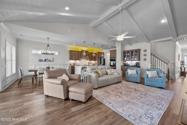 living room with beamed ceiling, dark wood-type flooring, ceiling fan with notable chandelier, and high vaulted ceiling