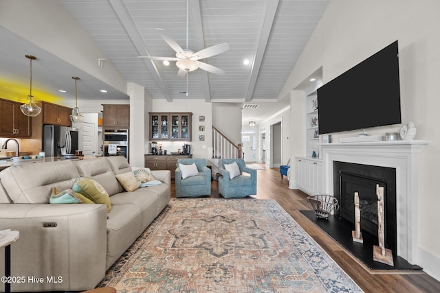 living room with built in features, lofted ceiling with beams, sink, dark hardwood / wood-style flooring, and ceiling fan