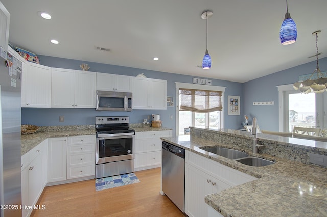 kitchen featuring white cabinetry, sink, hanging light fixtures, and appliances with stainless steel finishes