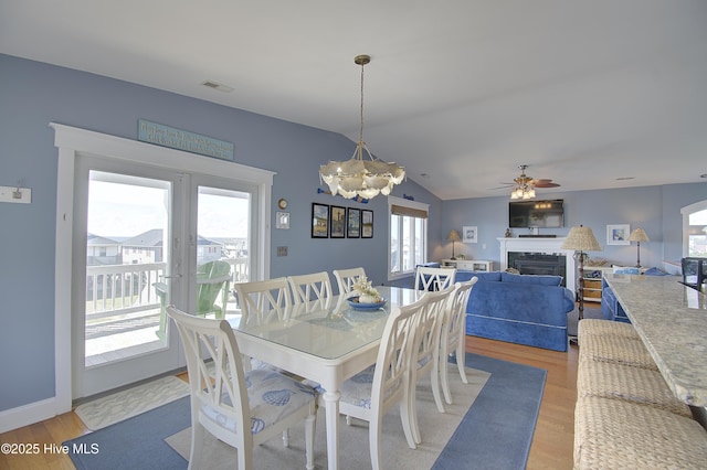 dining area with lofted ceiling, ceiling fan with notable chandelier, and light wood-type flooring