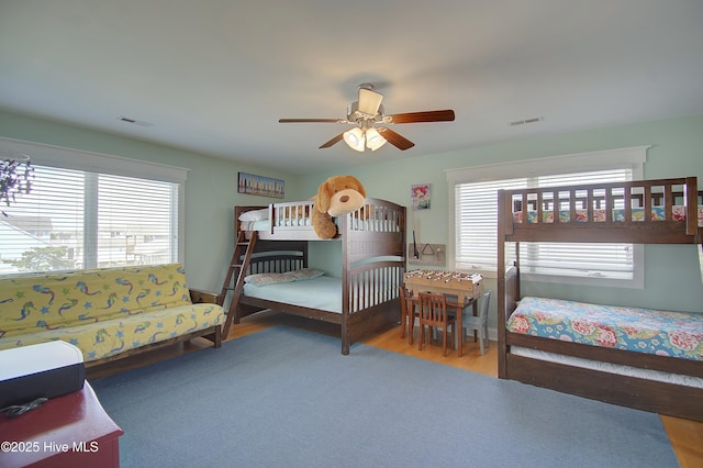 bedroom featuring ceiling fan, hardwood / wood-style floors, and multiple windows