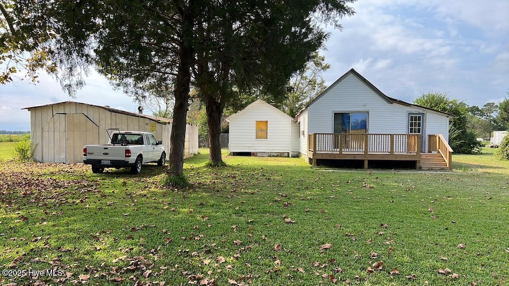 rear view of property with a wooden deck, an outbuilding, and a lawn