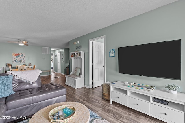 living room featuring dark hardwood / wood-style flooring, ceiling fan, and a textured ceiling