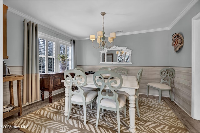 dining space featuring wood-type flooring, an inviting chandelier, and crown molding