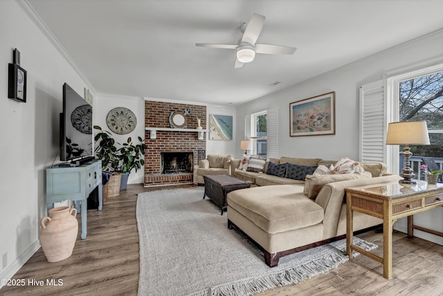 living room featuring ornamental molding, ceiling fan, light wood-type flooring, and a fireplace