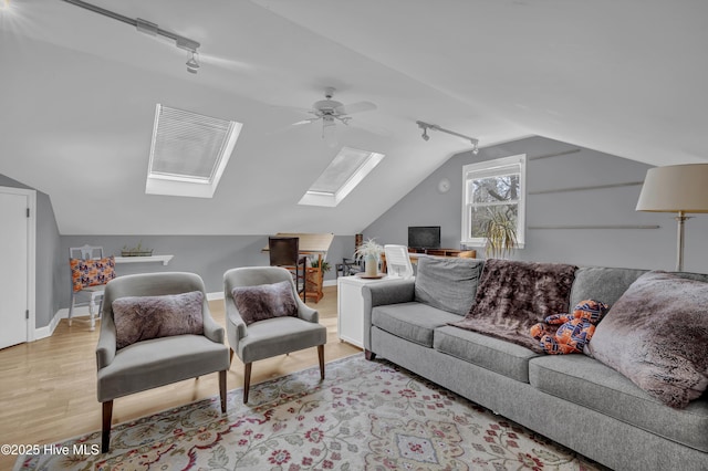 living room featuring ceiling fan, light wood-type flooring, vaulted ceiling with skylight, and track lighting