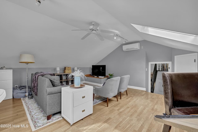 home office with ceiling fan, lofted ceiling with skylight, a wall mounted AC, and light hardwood / wood-style flooring