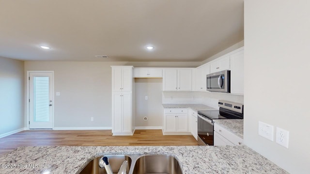 104 Bethany Pl, Goldsboro, NC 27530 - kitchen with appliances with stainless steel finishes, white cabinetry, backsplash, light stone countertops, and light wood-type flooring