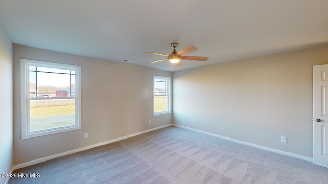 empty room featuring ceiling fan, a healthy amount of sunlight, and light carpet