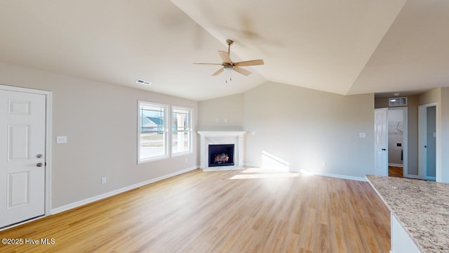 unfurnished living room with ceiling fan, vaulted ceiling, and light hardwood / wood-style flooring