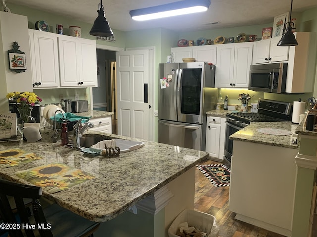 kitchen with hanging light fixtures, stainless steel appliances, sink, and white cabinets