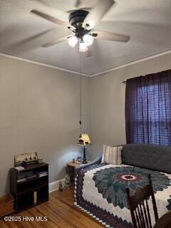 bedroom with hardwood / wood-style flooring, ornamental molding, and ceiling fan