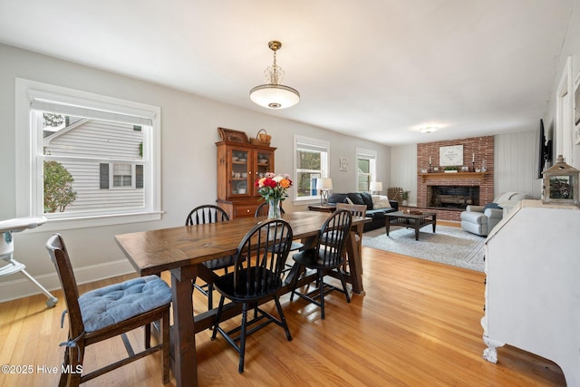 dining room featuring a brick fireplace and light wood-type flooring