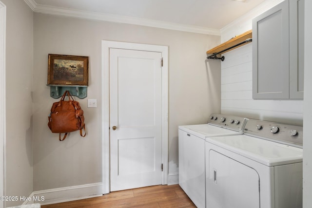 clothes washing area featuring crown molding, cabinets, washer and dryer, and light hardwood / wood-style flooring