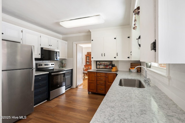 kitchen with dark wood-type flooring, sink, ornamental molding, stainless steel appliances, and white cabinets