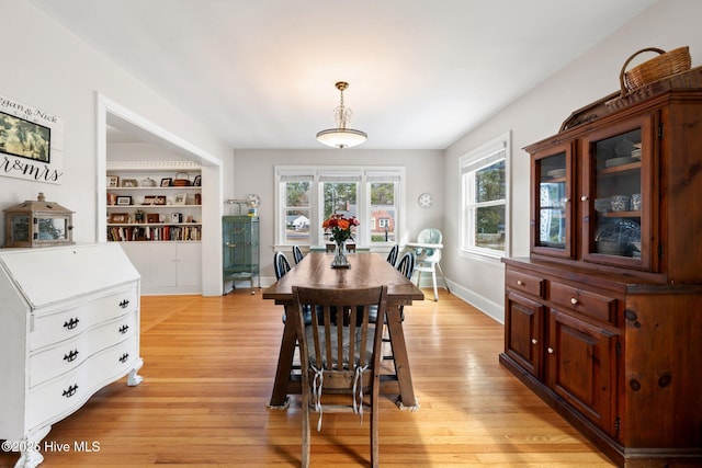 dining room featuring built in shelves and light wood-type flooring