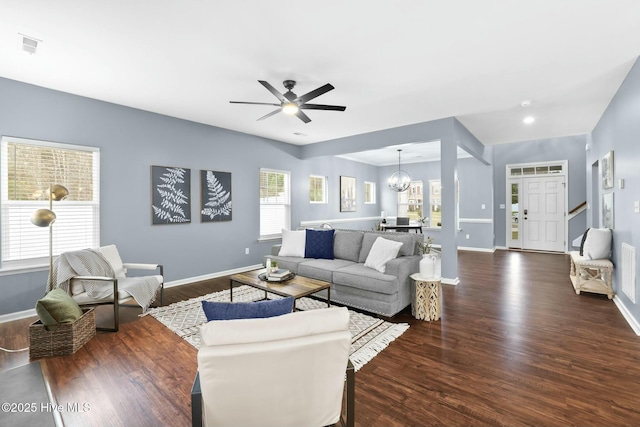 living room featuring a healthy amount of sunlight, ceiling fan with notable chandelier, and dark hardwood / wood-style flooring