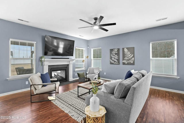 living room with ceiling fan, a multi sided fireplace, and dark hardwood / wood-style flooring