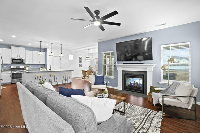 living room featuring dark hardwood / wood-style flooring, sink, and ceiling fan