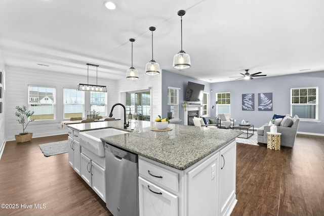 kitchen with sink, white cabinetry, light stone counters, a center island with sink, and stainless steel dishwasher