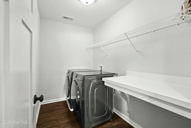 clothes washing area with dark hardwood / wood-style floors and separate washer and dryer