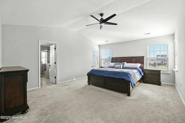 carpeted bedroom featuring ceiling fan, connected bathroom, vaulted ceiling, and multiple windows