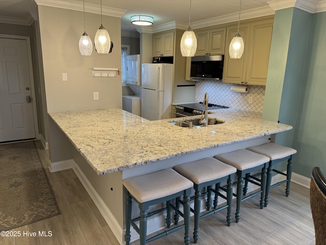 kitchen featuring white fridge, decorative light fixtures, a kitchen bar, and kitchen peninsula