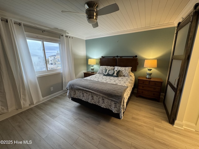 bedroom featuring crown molding, a barn door, and light wood-type flooring