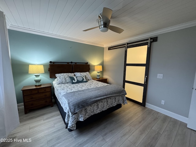 bedroom featuring ornamental molding, a barn door, and light hardwood / wood-style floors