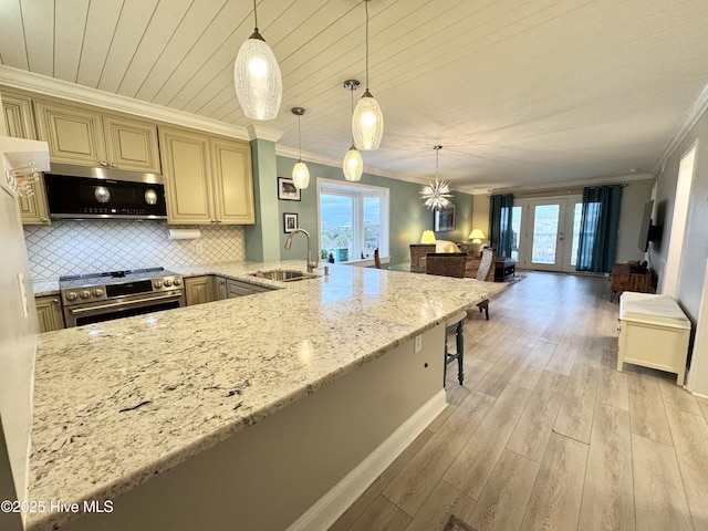 kitchen with pendant lighting, stainless steel appliances, light stone countertops, and sink