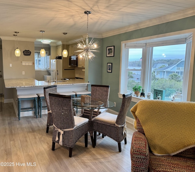 dining space featuring ornamental molding, light hardwood / wood-style flooring, and a wealth of natural light