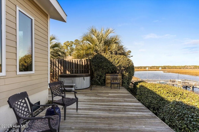 wooden deck featuring a water view and a hot tub