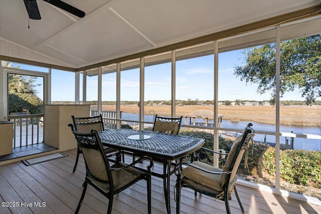 sunroom with ceiling fan and a water view